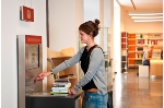 Eine Besucherin der Stadtbibliothek nutzt ein Selbstverbucher-Terminal in der Stadtbibliothek