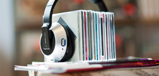 Eine Auswahl an Musik-CDs wird durch ein Headset zusammengehalten.
