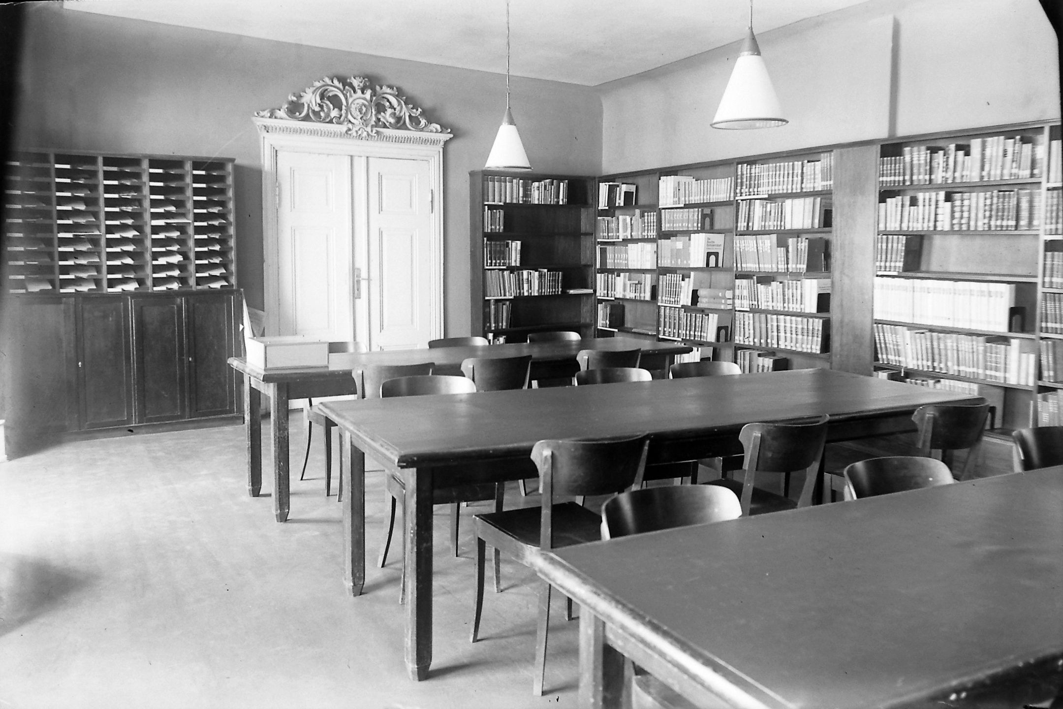 Ein Saal mit Regalen, Tischen und Stühlen in der Bibliothek im Jahr 1938.