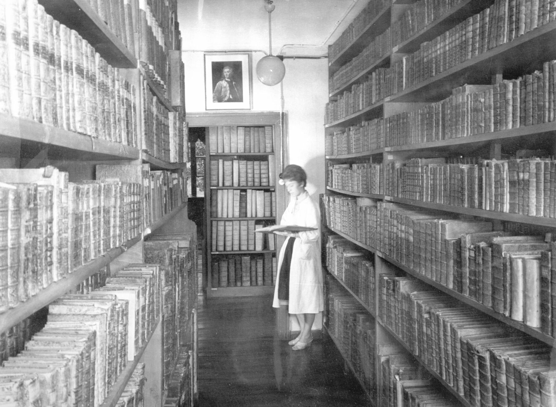 Eine Frau steht zwischen hohen Regalen der Bibliothek im Jahr 1961.