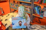 Ein Mädchen mit einer weißen Maske sitzt auf dem Boden und hält das Buch 