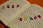 Kleine bunte Buchstaben stehen auf einem geöffneten Buch und bilden das Wort 