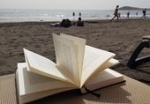 Ein Buch liegt auf einer Liege am Strand ausgebreitet